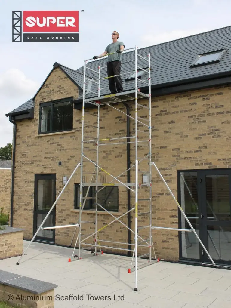 Super MDIY scaffold tower showing wide outrigger stabilization on a slight slope