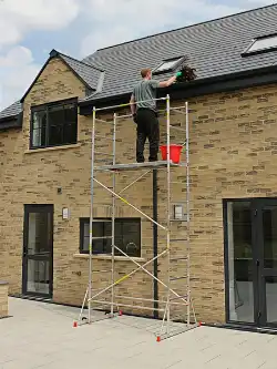 Cleaning house gutters using a LOYAL scaffold tower